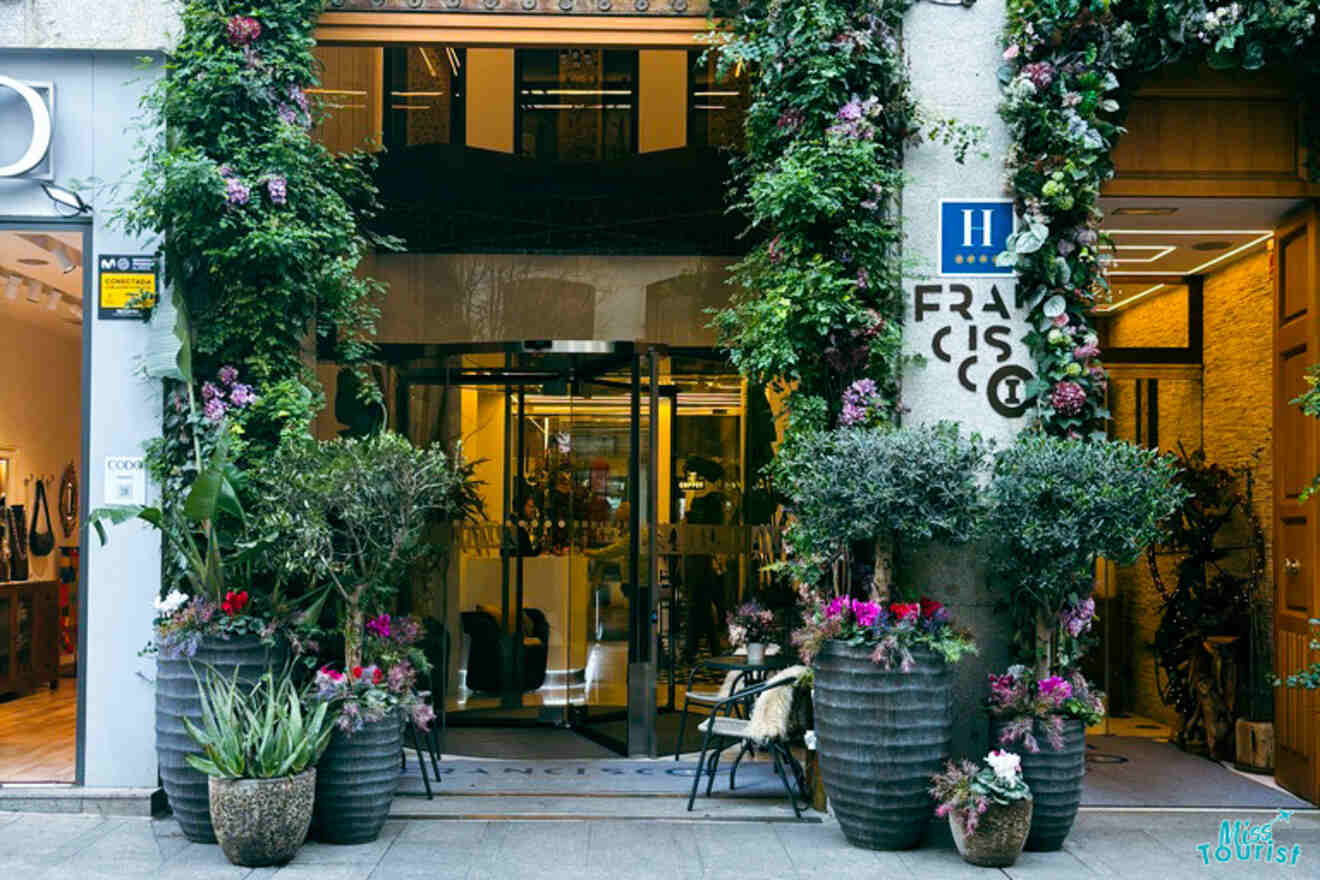 Entrance of the Francisco I Hotel in Madrid, adorned with lush greenery and vibrant flowers, creating an inviting atmosphere.