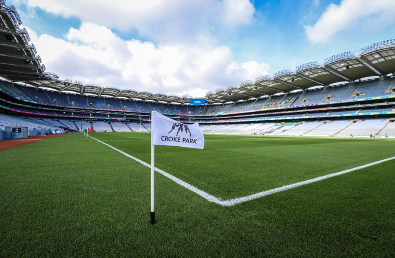 The Croke Park stadium in Dublin, with a close-up of the corner flag on the lush green pitch and the stands towering above.