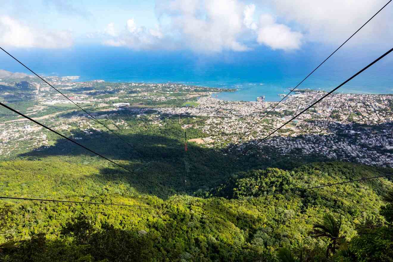 An aerial view of Puerto Plata from a cable car, showcasing dense greenery and the expansive coastline.
