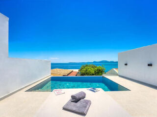 Rooftop plunge pool with ocean views under clear blue skies.