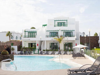 White buildings with green accents, around a serene pool area