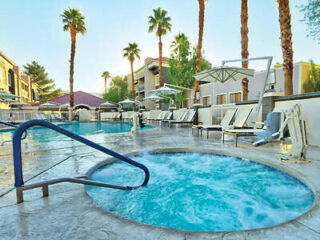 Tranquil hot tub area with palm trees and poolside lounge chairs