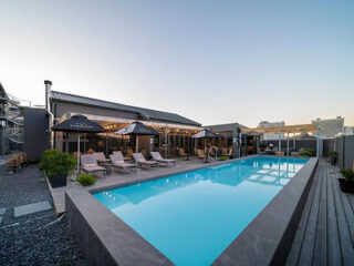 Luxurious hotel rooftop pool and lounge area at dusk, with stylish sunbeds