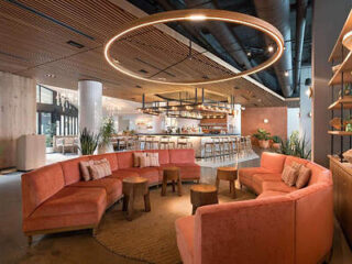 Trendy hotel interior with a modern bar area, chic coral sofas, and circular light fixtures