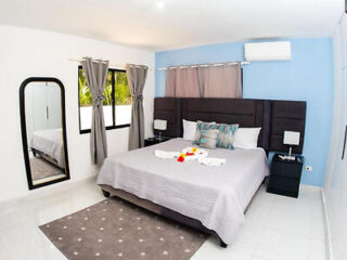 A spacious and modern bedroom with a king-sized bed, gray bedding, and contemporary furnishings.