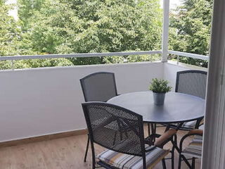 Intimate balcony setting with a round table and chairs, perfect for enjoying a morning coffee amidst urban greenery
