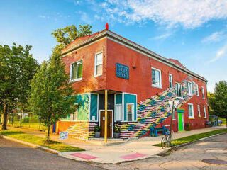 Colorful corner building with an artistic multicolored staircase, known as Hostel Detroit