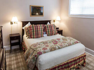Cozy bedroom with a classic decor, featuring a bed with floral bedding, plaid curtains, and bedside lamps