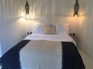 A serene bedroom featuring a bed with white bedding and a dark blue throw