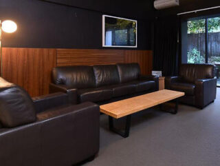Simplistic and functional common room with dark brown leather sofas and wooden tables