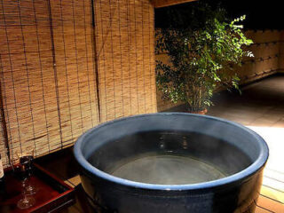 A tranquil outdoor private onsen (hot spring bath) on a wooden deck