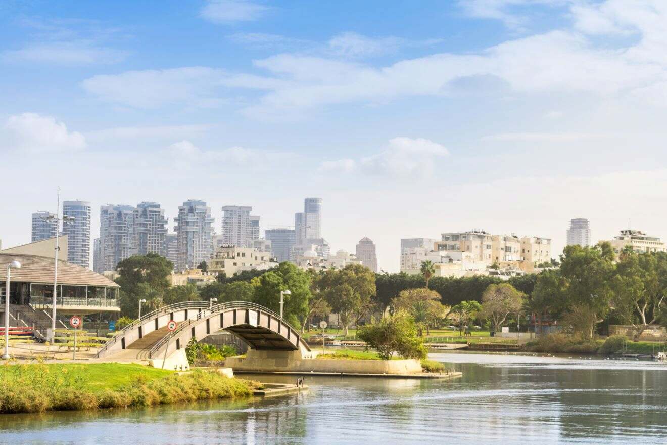 Serene cityscape of Tel Aviv with a bridge over the Yarkon River and skyscrapers in the background.
