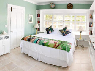 Spacious bedroom with a white bedspread, tile flooring, and a bright window