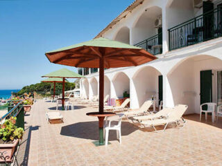 Seaside hotel terrace with sun loungers and parasols overlooking the ocean.