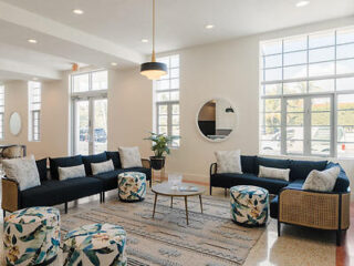 Spacious and stylish living area with large windows, comfortable seating, and a chic interior