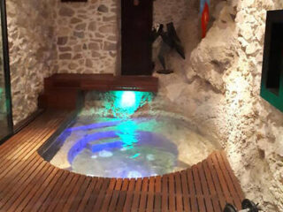 An intimate spa area in a stone-clad room with a small illuminated pool