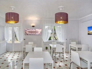 Modern, minimalist dining room with white furniture and chic patterned lampshades
