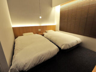 A compact and tidy twin bedroom in a Japanese hotel with clean white bedding