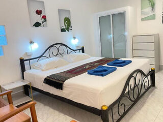 Simple and clean hotel room with metal bed frame and botanical artwork in Krabi