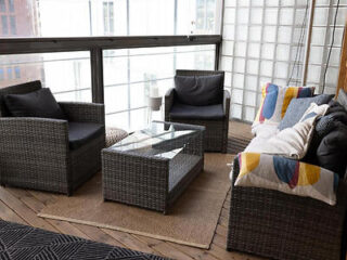Balcony seating area with rattan furniture, dark cushions, and a glass table