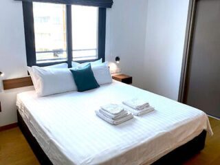 Minimalist bedroom with crisp white bedding, accent cushions, and a serene view for a restful night's sleep