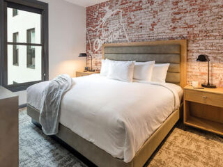 Urban bedroom with an exposed brick wall featuring a plush bed
