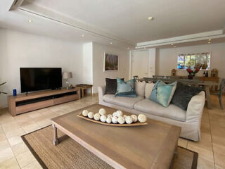 Spacious living area in an apartment with a plush sofa, wooden coffee table, and a large TV