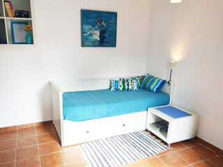 Charming small living space featuring a single bed with drawers, a compact coffee table, and vibrant throw pillows