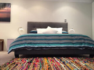 A cozy bed with a vibrant bedspread and a stylish rug