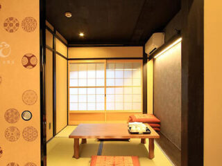 A warmly lit Japanese-style room with tatami flooring and a wooden low-rise table