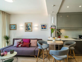 Cozy modern apartment living room with a lavender sofa and an integrated kitchenette