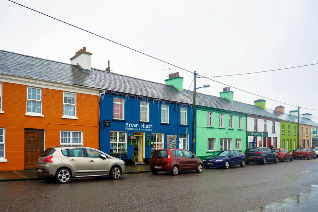 Colorful row houses lining a street in an Irish town with parked cars, exemplifying the quaint and vibrant architecture commonly found in Ireland's urban areas