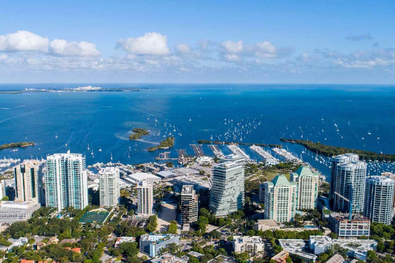 Aerial view of Coconut Grove's waterfront, showcasing a marina with boats and family-friendly green spaces.