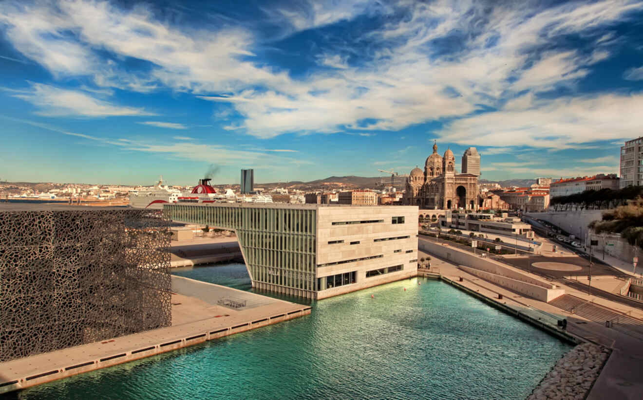 A scenic view of Marseille featuring the Mucem Museum and the historic Cathedral La Major under a picturesque cloudy sky