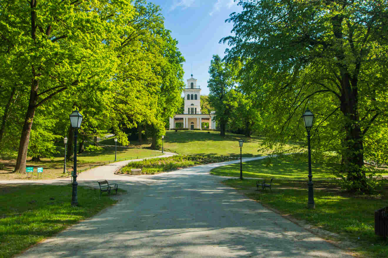 Lush Maksimir Park in Zagreb, showcasing a wide pathway leading to a charming pavilion, ideal for outdoor activities