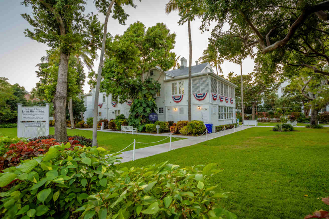 Historic Little White House in Key West with American flags and well-manicured green lawn