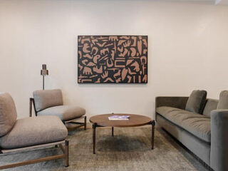 Contemporary lounge area with minimalist furniture, a large abstract painting, and a neutral color scheme