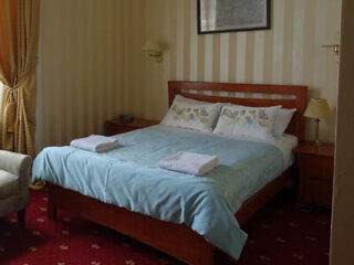 A traditional bedroom with a queen-size bed, soft blue bedding, and a vintage aesthetic