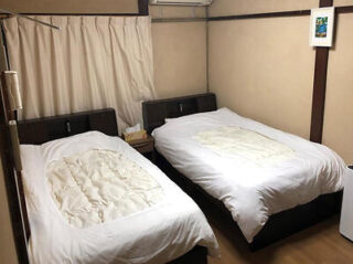 A simple, traditional Japanese bedroom with twin beds with white bedding