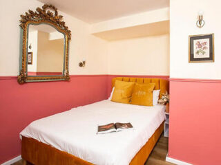 Quaint hotel room with a single bed and vibrant pink walls