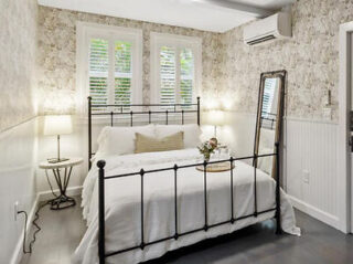 Rustic charm bedroom with wrought iron bed, stone accent wall, and soft lighting