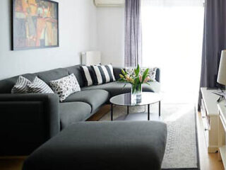 Contemporary living room in a modern apartment with a large gray sectional sofa and a round coffee table, complete with stylish throw pillows and fresh flowers