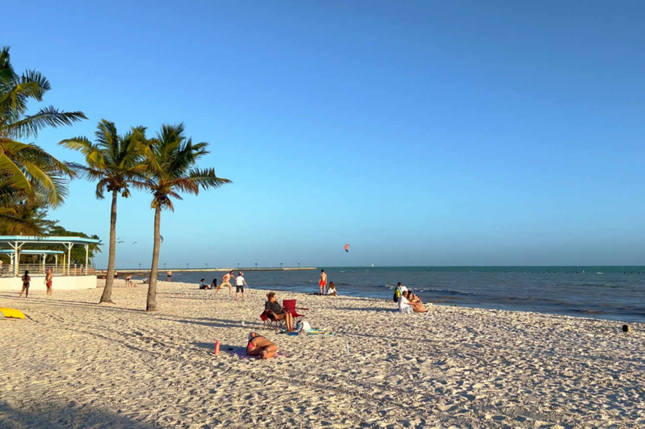 Relaxed beachgoers on the sandy shores of Casa Marina with palm trees and clear skies in Key West