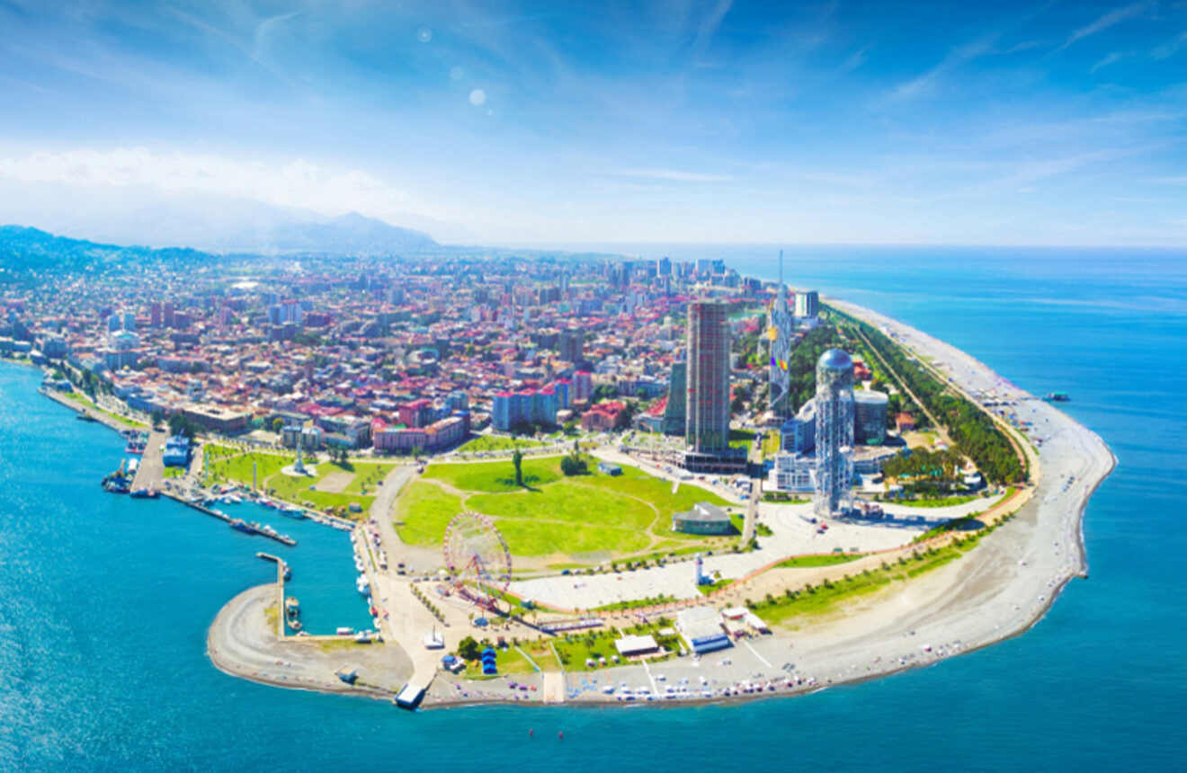 A bright, sunny aerial view of Batumi’s coastline, showcasing the city’s modern architecture and green spaces against the blue waters of the Black Sea