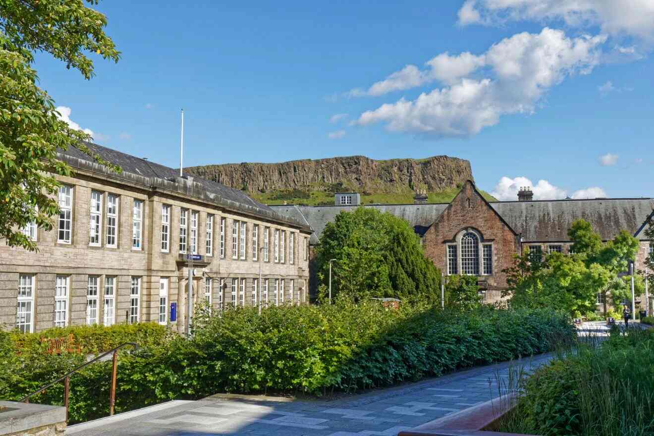 A serene educational campus in Edinburgh, with the majestic Arthur's Seat in the backdrop, lush greenery, and classic architecture
