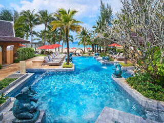 Elegant resort pool with statues and lounge chairs by the beach in Krabi