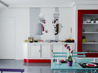 Contemporary kitchen with bold art on white walls, red accents, and a light blue dining setup