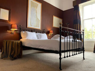 Luxurious bedroom with a classic wrought-iron bed, warm brown walls, and elegant gold accents