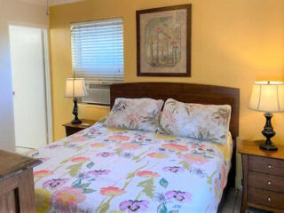 Warmly lit bedroom with a floral comforter, classic wooden furniture, and a soft yellow wall