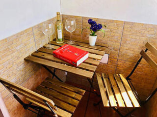 Rustic wooden bench and table set against a brick wall, adorned with a wine bottle and flowers